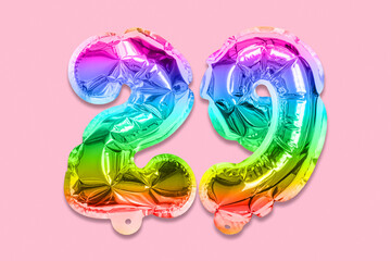 Fototapeta na wymiar Rainbow foil balloon number, digit twenty nine on a pink background. Birthday greeting card with inscription 29. Top view. Numerical digit. Celebration event, template.