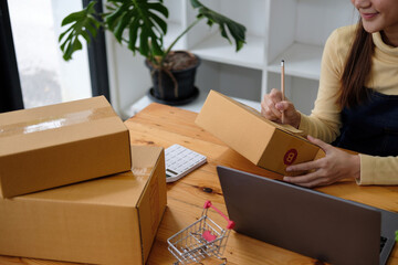 Starting small businesses SME owners female entrepreneurs writing address on receipt box and check...