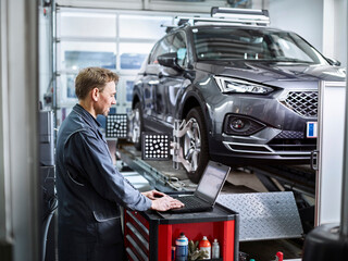 Car mechanic using laptop at auto repair shop