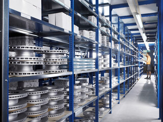 Technician in repair shop alley amidst racks with spare parts