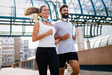 Happy runner couple exercising outside as part of healthy lifestyle. People sport running concept