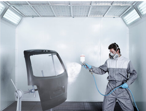 Painter spray painting door at repair shop