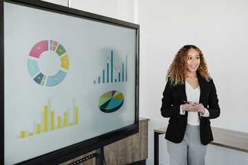 Young businesswoman with hands clasped giving presentation in board room
