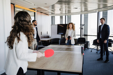 Businesswomen playing table tennis enjoying with colleagues in office