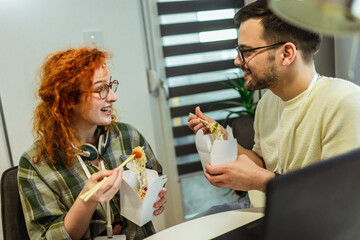 Couple working at home eating chinese food ordered online.