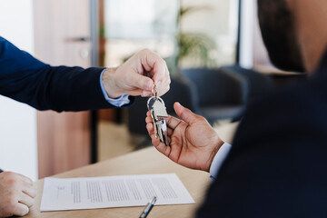Real estate agent giving house keys to buyer in office