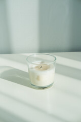 White aroma candle for spa in a bottle on a white table. Minimalism.