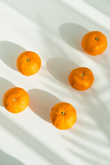 Five tangerines on a white table with the shadow of palm leaves. Flat lay, top view, aerial. - 485516461