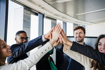 Happy business colleagues with stacked hands in office
