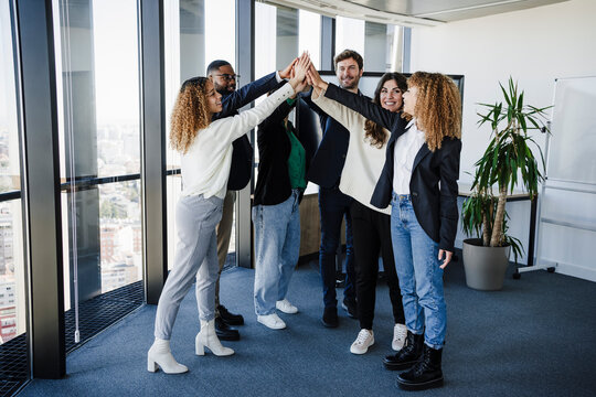 Multi-ethnic business colleagues stacking hands in office