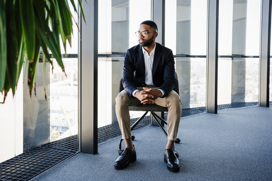 Young Businessman With Hands Clasped Sitting On Chair In Office