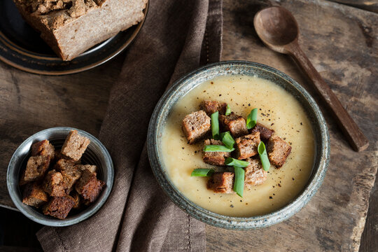 Homemade Jerusalem Artichoke soup garnished with croutons and scallions in bowl