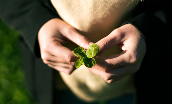 Young woman holding green four-leafed clover