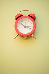 new red round clock on pale green table, copy space.