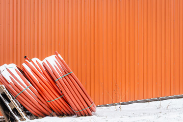 Coiled red plastic pipes stored winter outdoors near orange,background,selective focus,copy space.