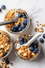 Granola with nuts, yogurt and berries in jar. Breakfast parfait with muesli, yoghurt and blueberries, white background.