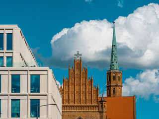 Fototapeta na wymiar modern business center and old gothic catholic church on a blue sky background. european urban environment