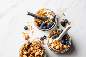Granola with nuts, yogurt and berries in jar. Breakfast parfait with muesli, yoghurt and blueberries, white background.