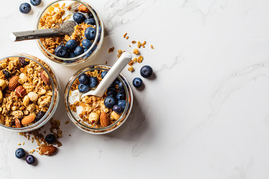 Granola With Nuts, Yogurt And Berries In Jar. Breakfast Parfait With Muesli, Yoghurt And Blueberries, White Background.