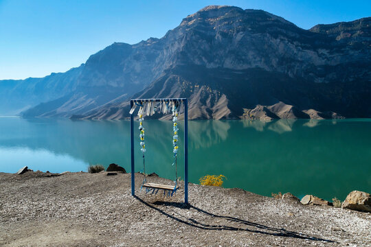 Empty swing overlooking mountain lake