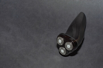 Glossy black electric razor for men on a black background