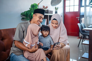 family muslim with two little children looking at mobile phone