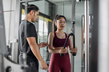 Asian woman exercise with personal trainer in gym. Young healthy woman workout in fitness with personal coach.