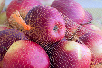 The ripe of apples packaged in the plastic net. Sale of fruits in the supermarket.
