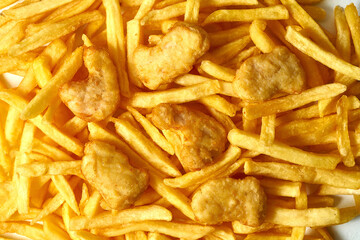 Close-up on the chicken nuggets from above. The nuggets lie on top of the fries