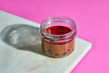 Cherry and chocolate souffl? in a glass jar on a marble board on a pink background