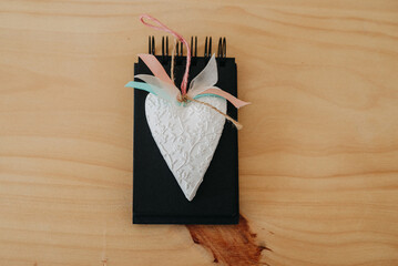 notebook with black sheets on a wooden table with a white heart.