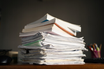A pile of paper sheets and books on a table