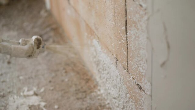 A wall being covered in a layer of plaster. LD Plaster being sprayed onto an inside wall
