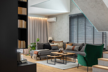 Stylish composition of living room interior with corner grey sofa, green velvet armchair, coffee table, wooden floor, design furniture and personal accessories. Modern home decor. Template.
