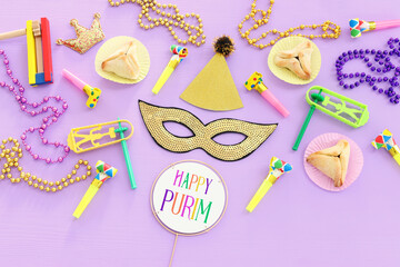 Purim celebration concept (jewish carnival holiday) over wooden purple background. Top view, flat lay