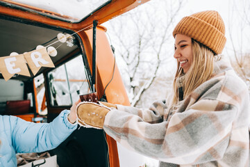 Young caucasian woman taking mug with hot tea near van , in winter time outdoor, during road trip.