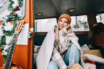 Portrait of cheerful young woman sitting in a van in winter camp.
