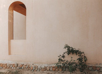 An arch window in the wall of the arabic building. Light summer shadows on the wall. - 485527641