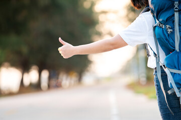 happy hitchhiker asian woman thumb up for car transportation for backpack travel for relax in long vacation in holiday