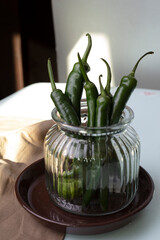 green chili pepper on a light background in a glass jar