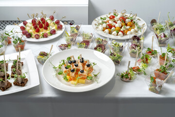 Canape with shrimp, pineapple and olives - festive bright appetizer on white plate. The food is garnished with pea sprouts.