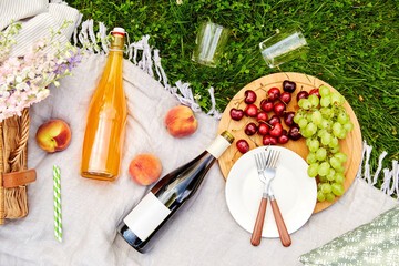 leisure and drinks concept - close up of food, drinks and basket on picnic blanket on grass