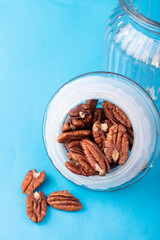 Peeled pecans on a blue background in a jar for bulk