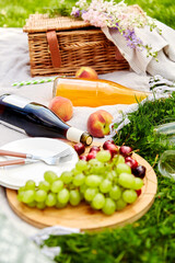 leisure and drinks concept - close up of food, drinks and basket on picnic blanket on grass