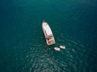 Drone shot of the beautiful white yacht in the warm blue sea; wealth concept.