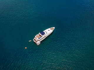 Drone shot of the beautiful white yacht in the warm blue sea; millionaire concept.