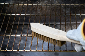Wooden wire brush cleans dirty barbecue grill rust. Leather protection gloves.