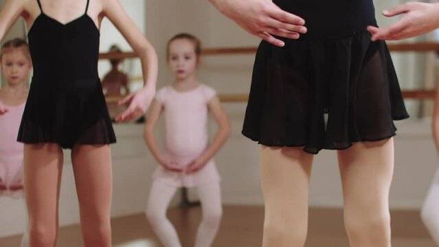 Ballet training - little ballerina girls squatting in the studio