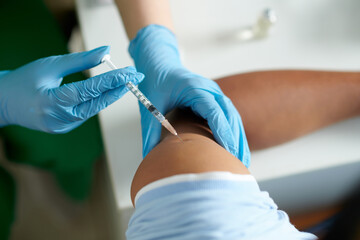Closeup image of nurse in medical gloves revaccinating patient with vaccine against new stamp of...