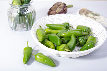 green jalapeno peppers in a white wicker basket on a light background